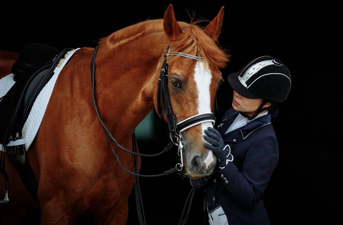 Woman caring for her horse outside of stables.